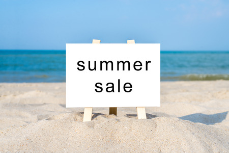 Wooden blank white board on sunny sandy beach.の写真素材