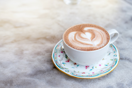 A coffee of white cup with foam in the form of heart on gray rock table, copy space.の写真素材