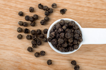 Black pepper corn in wooden background