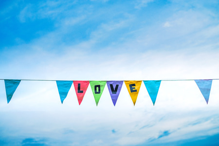 Multicolored flags on the blue sky with message of loveの写真素材
