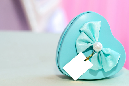 Blue heart box decorated with ribbon and pearls placed on the table.の写真素材