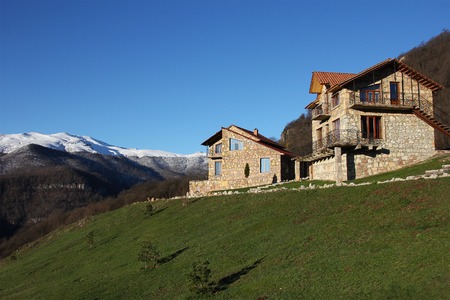 two stone houses on the hill on the background of snowy mountains, clear blue sky, horizontal, Armeniaの写真素材