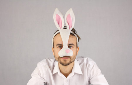 man in white shirt and in the mask Easter rabbit looking at camera, studio