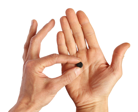 human picks up  one black pill from palm, closeup, isolatedの写真素材