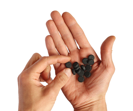 human pick one pill from palm with black pills, closeup, isolatedの写真素材