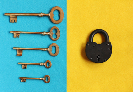 five different golden keys on blue background and close padlock on yellow background, closeupの写真素材