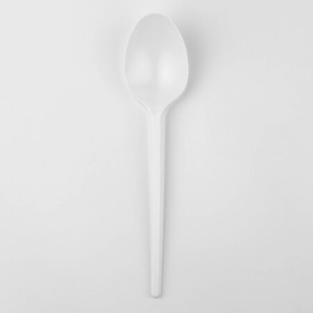clear white plastic kitchen spoon, tablespoon on white background, ecological problem, closeup, square photoの写真素材