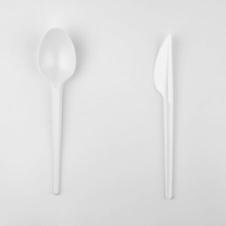 clear white plastic kitchen spoon, tablespoon and back side of knife on white background, ecological problem, closeup, square photoの写真素材