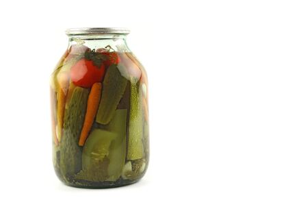 jar with pickled vegetables, marinated and canned cucumbers carrots and tomatoes, traditional russian meal for winter, vegetarian food vitamins and nutrients, white background, copy space on the right の写真素材