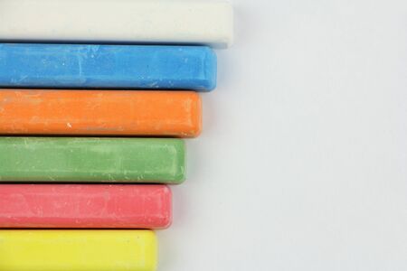 six colored children crayons on white background, different colors chalks for school or preschool activities, blue red green yellow orange white, on left side, top viewの写真素材
