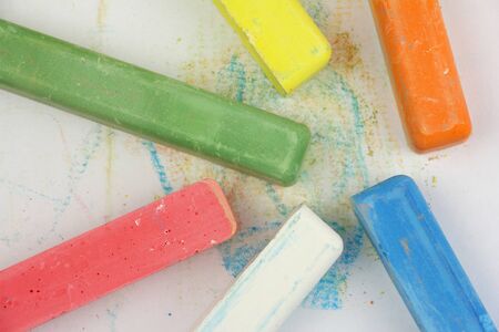 colored children crayons scattered on white paper, different colors for school or preschool activities, top viewの写真素材