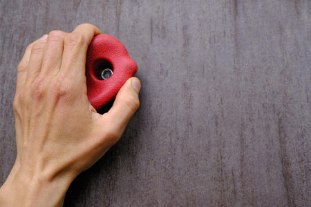 human hand holds on red climbing hold on artificial climbing wall, concept of sport education,...