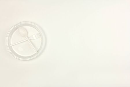 used dirty plastic disposable tableware, plate fork spoon, on white background, top view, copy space, concept of pollution and environmental problemの写真素材