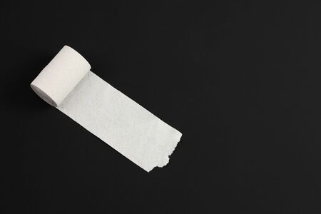 unrolled roll of rough recycled white toilet paper on black background, close-up top view, copy space, concept of notebook for recording thoughts or diarrheaの写真素材