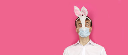 banner with frightened man in mask Easter Bunny and medical mask look ahead, virus or coronavirus protection and prevention before holiday, preparation for party, copy spaceの写真素材