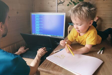 Busy father freelancer try to work from home in quarantine and his son child plays near himの写真素材