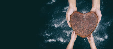Father baker hands gives vegan rye whole grain yeast-free sourdough bread in shape heart to son kid