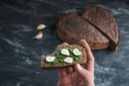 Hand holds bitten sandwich artisan bread with onion chives and garlicの写真素材