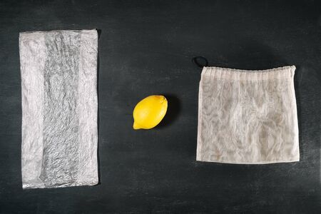 Fresh yellow lemon between plastic package and eco grocery meshの写真素材