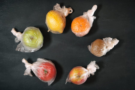 Colored fruits in the plastic package on blackの写真素材