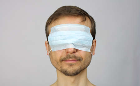 head of happy smiling man with medical protective mask on his eyes, virtual reality and entertainment during isolation, new normalの写真素材