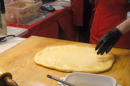 chef prepare dough for traditional czech bakery trdelnik, national pastry food on street Christmas market, hands in rubber glovesの写真素材