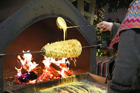 cooking traditional Lithuanian dish shakotis or raguolis over an open fire in vintage oven on street Christmas marketの写真素材