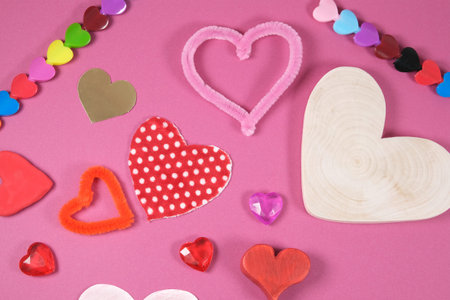 many of craft valentine hearts shapes made from different materials, wood plastic textile fabric, handmade creative gifts on pink backgroundの写真素材