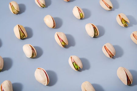 diagonal arranged rows of fresh pistachio nuts with hard shadows, good source of healthy vegetable...