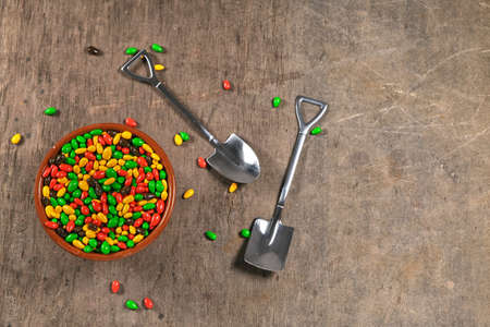 sunflower seeds in chocolate colored glaze in cup with two teaspoons in shape of shovel, concept of sugar addiction, on wooden background with copy spaceの写真素材