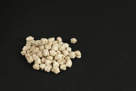heap of white dried chickpeas on black background with copy space, food with vegetable protein, side viewの写真素材