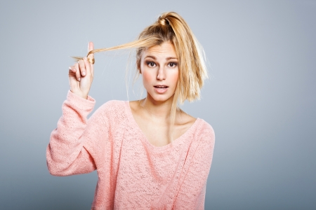 Young Blond Girl with Hair Problems ona Grey Backgroundの写真素材