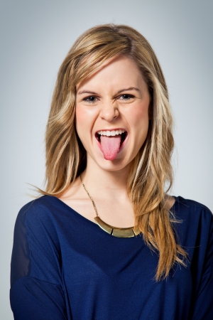 Funny Teenager Showing her Tongue in a Grey Backgroundの写真素材