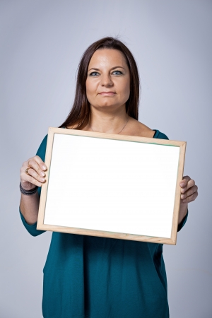 Teacher Showing a Blank White Board on a Grey Backgroundの写真素材