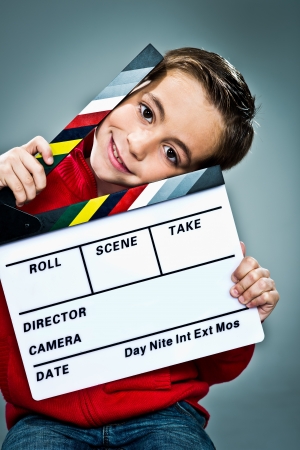 Little Actor with a Slate in His Head over a Grey Backgroundの写真素材