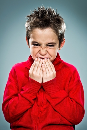 Funny Kid Eating His Nails on a Grey Backgroundの写真素材