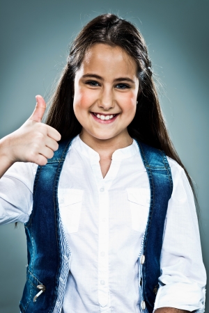 Cute Little Girl Woman Doing an OK Sign Over a Grey Backgroundの写真素材