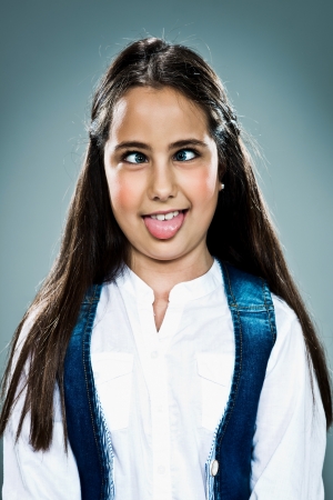 Cute Little Girl with Funny Expression with Funny Expression over a Grey Backgroundの写真素材