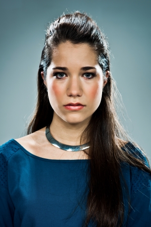 Young Woman with Serious Expression over a Grey Backgroundの写真素材