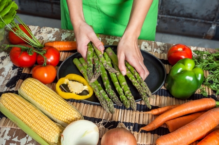 Woman Hands Preparing Raw Veggies on a Wooden Tableの写真素材