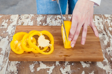 Woman Cutting a Yellow Pepper on a Wooden Boardの写真素材