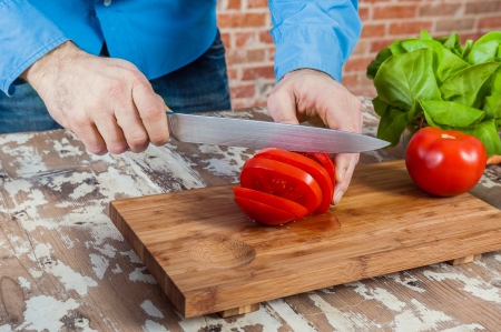 Man Cutting Tomatoes in a Wooden Boardの写真素材