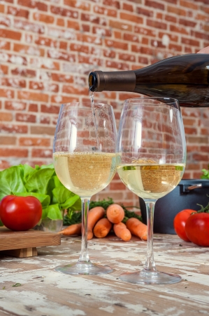 Pouring White Wine in the Kitchen with Veggiesの写真素材