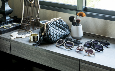 handbag,sunglasses, jewelry and makeup brushes on a black tableの写真素材