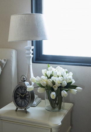 white lamp and alarm clock on bedside tableの写真素材