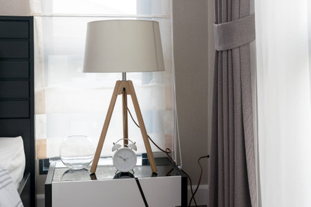 modern bedroom with wooden lamp and alarm clock on bedside table