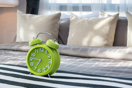 modern bedroom with green alarm clock on bedの写真素材