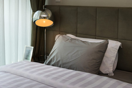 metal desk lamp and grey pillow on bed