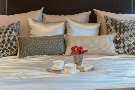luxury bedroom interior with brown pattern pillows and decorative tray of flower on bed