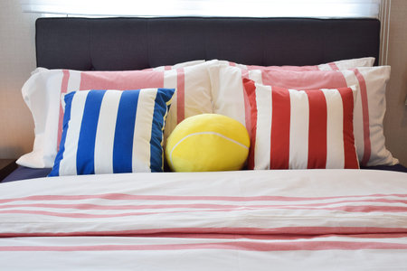 Modern bedroom interior with blue,yellow and red striped pillows on bed
